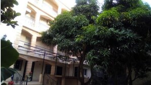 A multi-story building with a balcony on the second floor and a tree in the foreground. - 4-bedroom apartment near the beaches and attractions • Gated and secure residential community • The Beleric (Dakar)