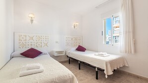 A hotel room with two beds, a window with curtains, and decorative wall panels.