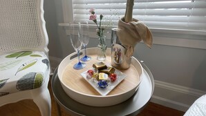 A table with a bottle of champagne, two glasses, a vase with flowers, and a plate with chocolates. - The Boardwalk Inn  (Summerside)