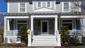 A two-story house with a front porch, a welcome sign, and a number '156' on the door. - The Boardwalk Inn  (Summerside)