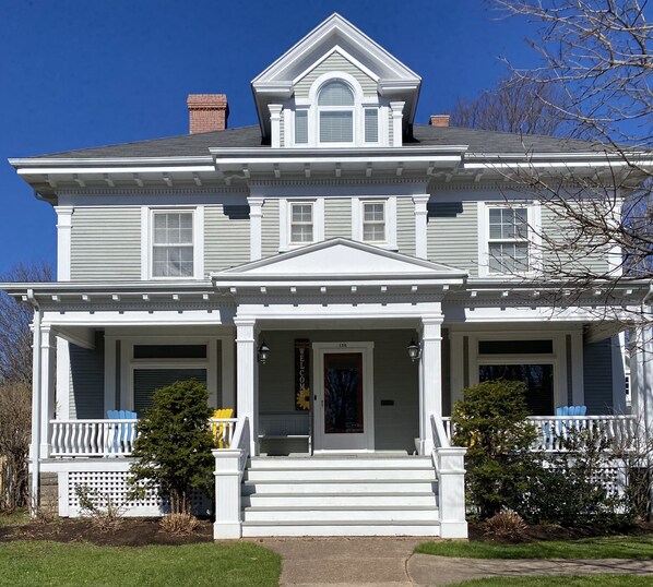 A two-story house with a front porch, a welcome sign, and a number '156' on the door.