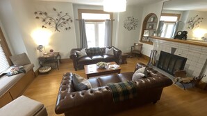 A living room with a fireplace, leather sofas, a coffee table, and decorative wall art. - The Boardwalk Inn  (Summerside)