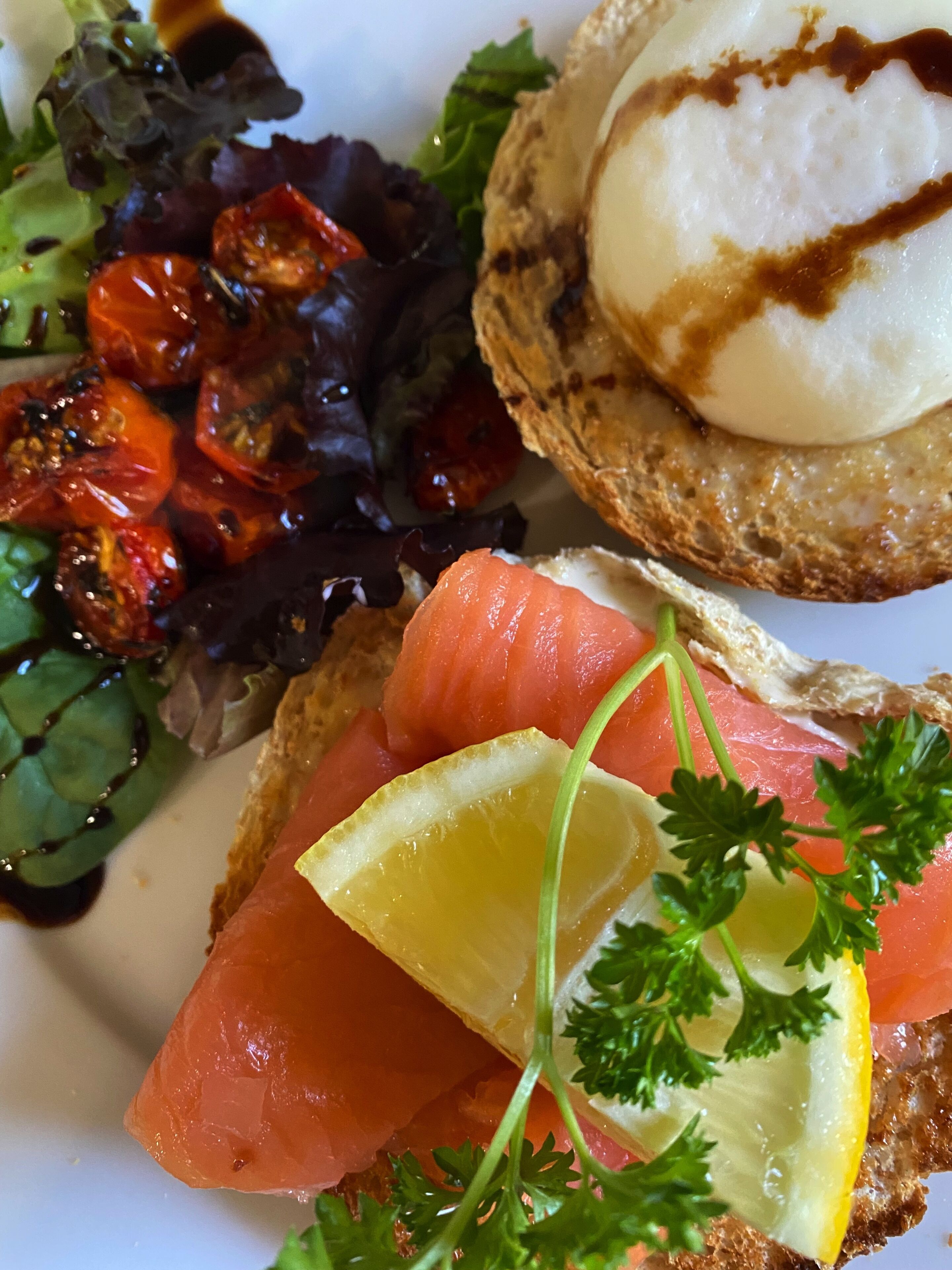 A plate with smoked salmon, lemon, parsley, and a poached egg on toast.