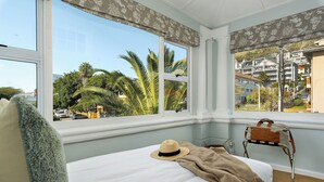 A bedroom with a large window, a bed, a suitcase, and a chair. - Neighbourgood Hill (Cape Town)