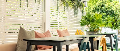 An outdoor patio with a wooden deck, a sofa with cushions, a table, and chairs.