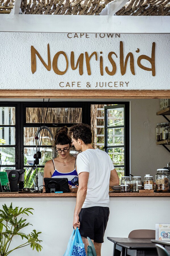 A cafe named "Nourishd" with a rustic interior, a counter, and a window view. - Neighbourgood Hill (Cape Town)