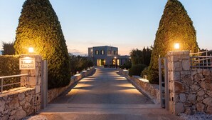 A villa with a stone entrance, a paved driveway, and a well-maintained garden with tall trees. - TIMORI, modern, panorama views, pool & kiddie-pool, 4 bedrooms plus guest house. (PLAKA)