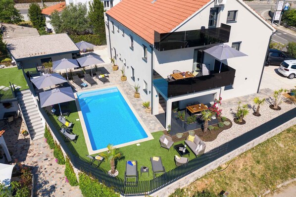 Un bâtiment moderne doté d’une piscine, d’un espace extérieur aménagé et d’un jardin clos.