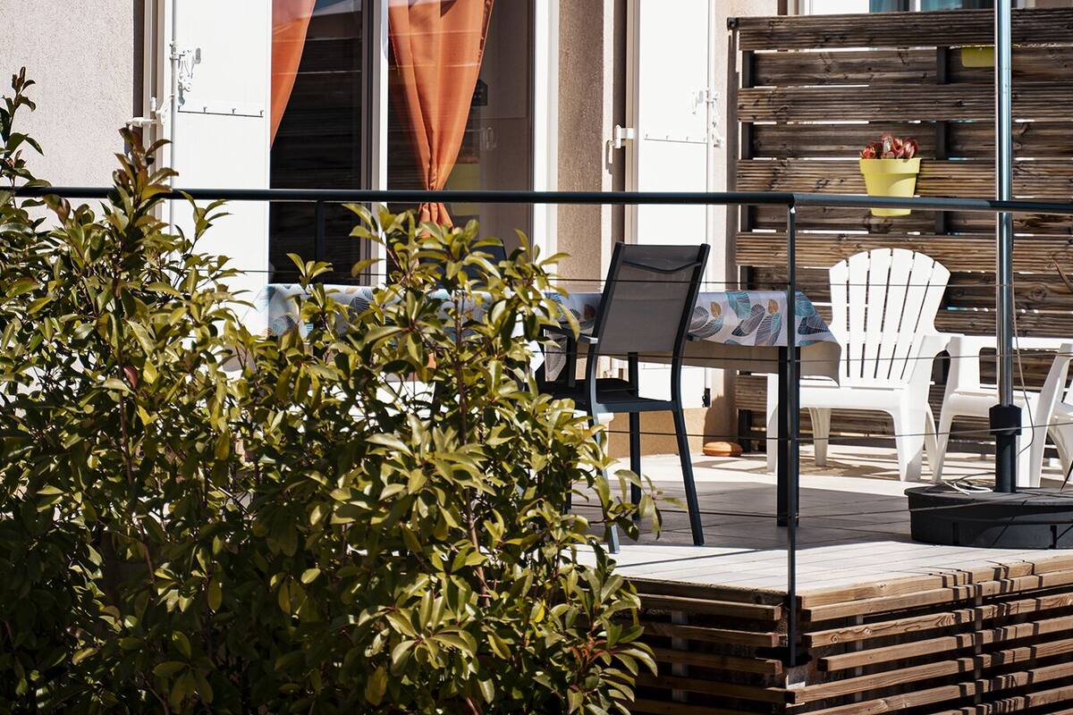 Eine Terrasse mit Tisch, Stühlen und einer Satellitenschüssel an einem Gebäude.