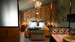 Une chambre avec deux lits, un grand miroir, un plancher en bois et une salle de bain avec un grand lavabo et un miroir.