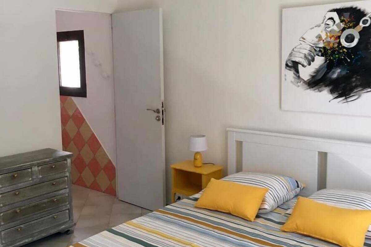 Ein Schlafzimmer mit Bett, Schminktisch, Tür, Nachttisch und Deckenleuchte.