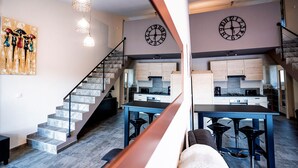 Une cuisine moderne avec un îlot central, un escalier et un coin repas.