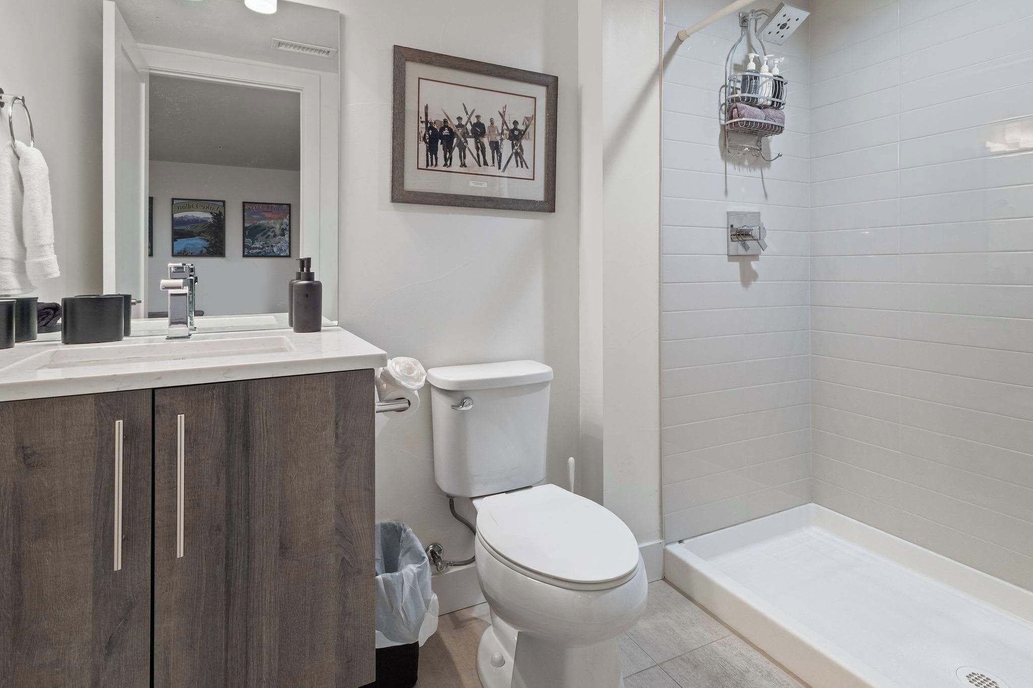 A modern bathroom with a toilet, vanity, and shower.