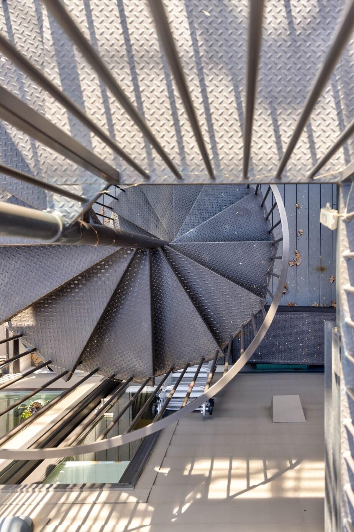 A spiral staircase with a metallic finish and a diamond plate pattern on the steps.