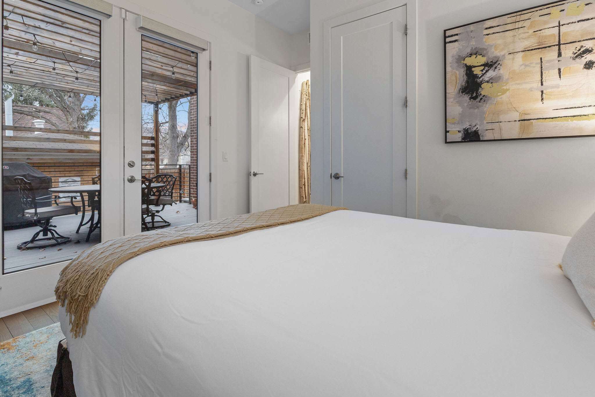 Une chambre avec un grand lit, une porte-fenêtre coulissante donnant sur un espace extérieur et un tableau accroché au mur.