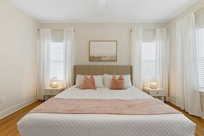 Une chambre à coucher avec un lit, deux tables de chevet, une tête de lit et un tableau au mur.