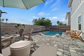 Un jardin avec une piscine, une terrasse en bois et du mobilier d’extérieur.