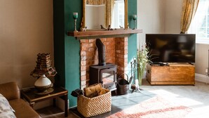 Uma sala de estar acolhedora com lareira de tijolos, televisão e um espaço de estar confortável.