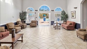 A spacious lobby with a tiled floor, two sofas, a coffee table, and a large arched window. - 2BR Nemo Condo near Disney | Gated with Pool (Kissimmee)