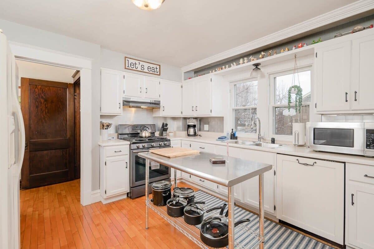 Una cocina moderna con gabinetes blancos, una estufa de acero inoxidable y una isla central.