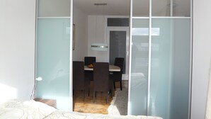 Quarto com porta de correr de vidro que dá para uma sala de jantar com mesa e cadeiras.