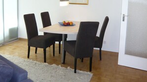 Uma área de refeições moderna, com uma mesa redonda, seis cadeiras e uma obra de arte emoldurada na parede.