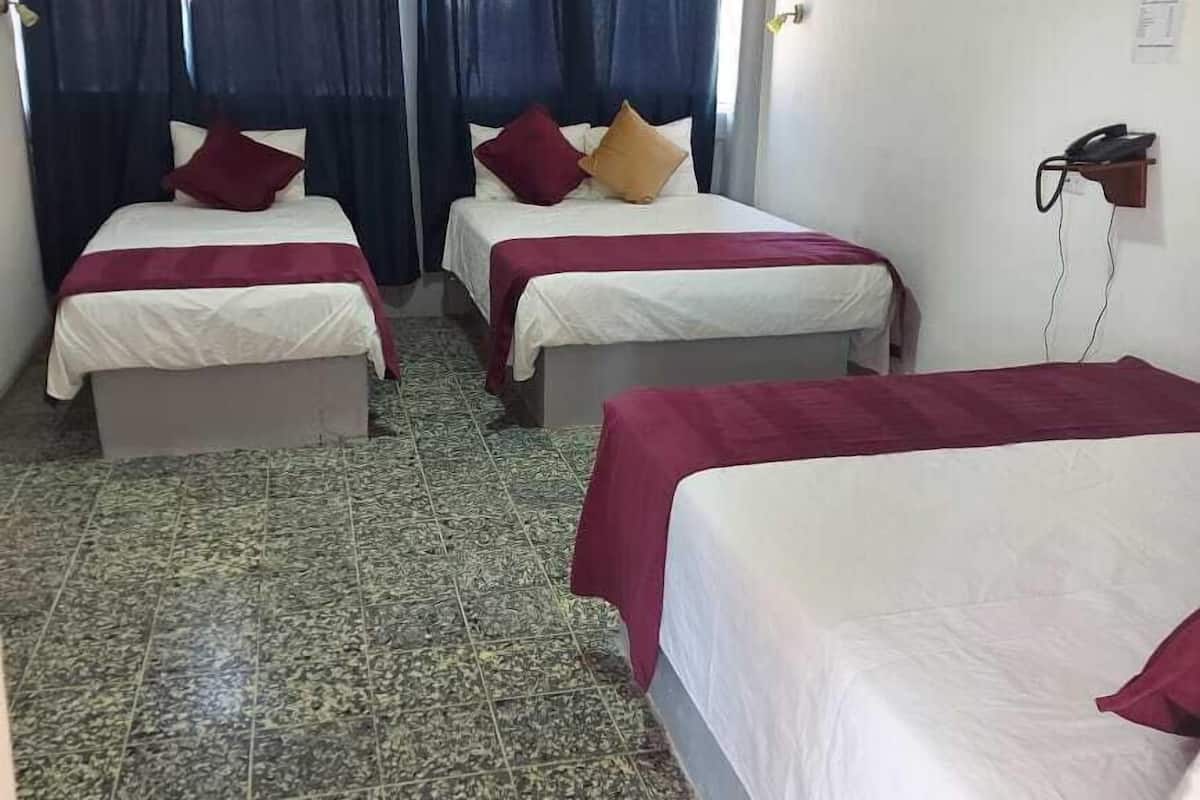 Una habitación de hotel con dos camas, piso de baldosas y aire acondicionado instalado en la pared.