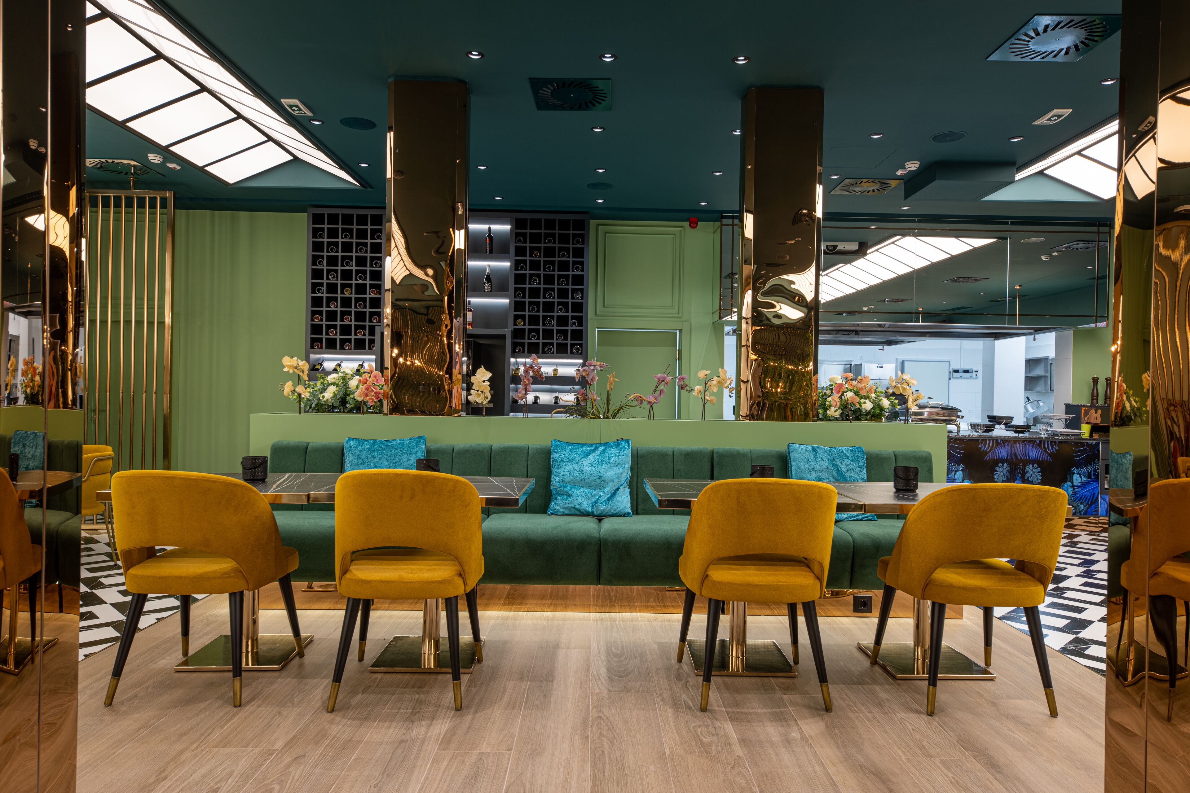 Un intérieur moderne avec un canapé vert, des chaises jaunes et un sol à carreaux.
