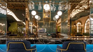 Un espace bar luxueux, doté de comptoirs en marbre, de chaises recouvertes d’un tissu bleu et de luminaires décoratifs.
