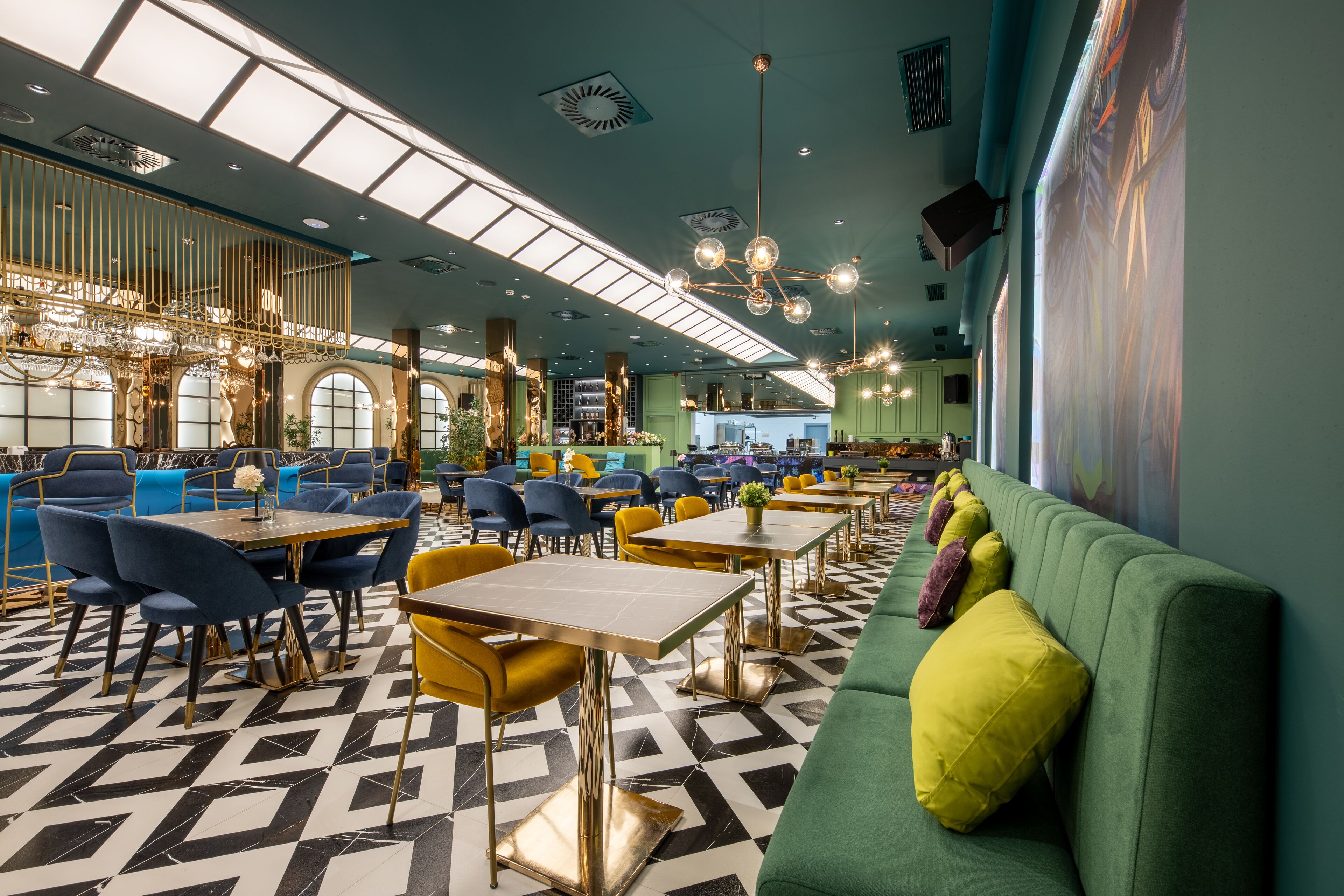 Un restaurante espacioso con techos altos, iluminación moderna y un patrón geométrico en el suelo.