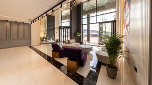 Un hall d’entrée spacieux doté d’un sol en marbre, de meubles modernes, de grandes fenêtres et d’un plafond décoratif.