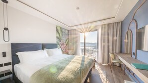 Hotellihuone, jossa on suuri sänky, työpöytä ja näkymä kaupunkiin.