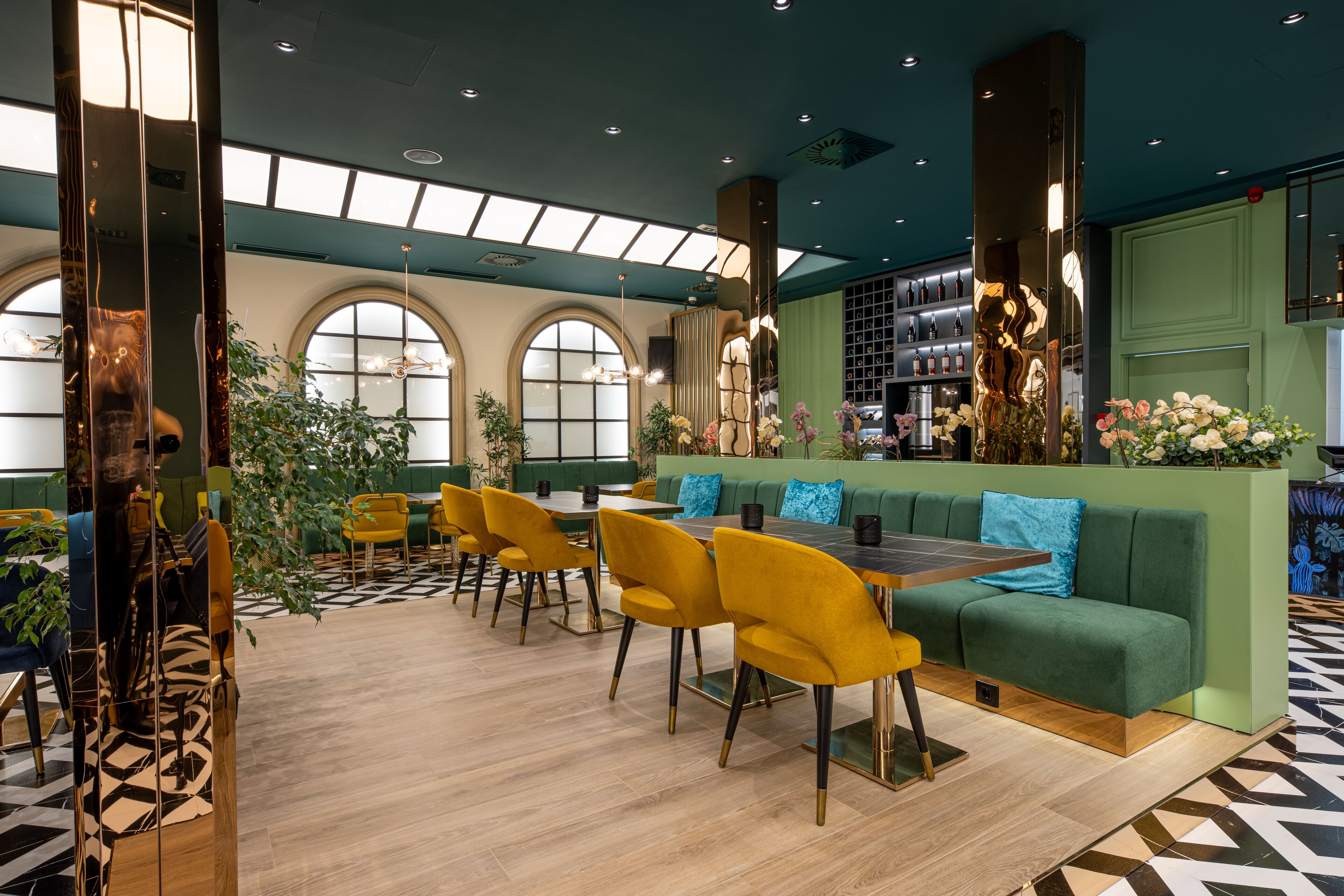 Un interior moderno con un sofá verde, sillas amarillas y una mesa de madera.