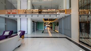 A modern lobby with a glass ceiling, a reception desk, and seating areas.