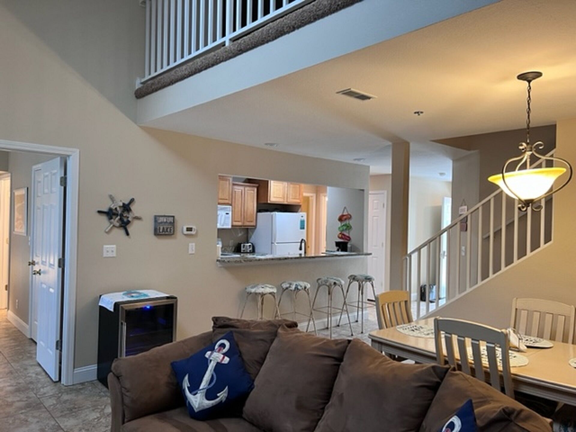A living room with a brown sofa, a TV, and a dining area with a table and chairs.