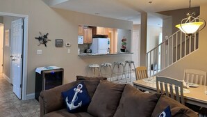 Uma sala de estar com um sofá marrom, uma televisão e um espaço de jantar com mesa e cadeiras.