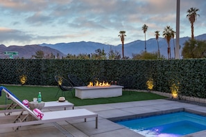 A pool area with lounge chairs, a fire pit, and a view of mountains. - Picture Perfect Retreat – Modern Hollywood Glam (Palm Springs)