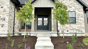 A stone house with a dark front door, two trees in front, and a number 734 on the left side. - New Heber home near Park City. 7brm/5.5ba with hot tub, pickleball, sleeps 18. (Heber City)