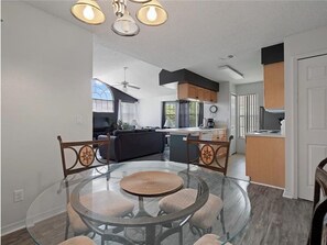 Enjoy meals around the central dining table in this open-plan living space, featuring a kitchen with cabinetry and island.