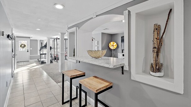 A modern kitchen with a marble countertop, two wooden stools, and a decorative vase on the wall. - Relaxing Retreat  (Westminster)
