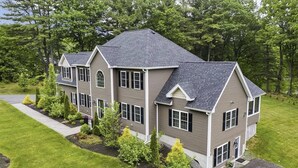 A two-story house with a symmetrical design, a covered front porch, and a well-maintained lawn. - Relaxing Retreat  (Westminster)