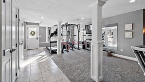 A spacious home gym with a pull-up bar, weight bench, and various exercise equipment. - Relaxing Retreat  (Westminster)