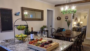 A kitchen with a marble countertop, a fruit bowl, a cheese board, and a wine bottle. - The Little River Farmhouse – Your Smoky Mountain Riverside Retreat (Townsend)