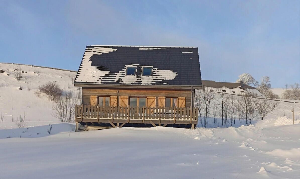 A wooden cabin with a porch, surrounded by snow.