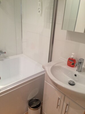 Bathroom features a bathtub, sink, and mirror.