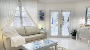 A modern living room with a beige sofa, a white coffee table, and a patterned rug.