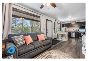 Relax in a serene space with a sofa, decorative pillows, and a view of the surrounding trees.