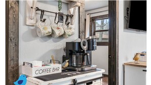 Un coin café équipé d’une machine Keurig, d’un présentoir à tasses et d’une statuette d’oiseau.