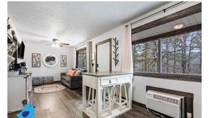 Un salon chaleureux avec une cheminée, un canapé et un coin repas comprenant une table et des chaises.