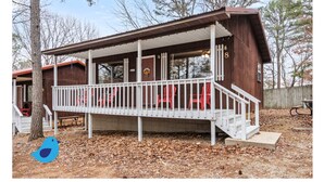 Une cabane en bois avec une véranda, un escalier et une table de pique-nique.
